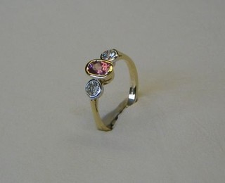 A lady's modern 18ct gold dress ring set a pink sapphire, supported by 2 diamonds