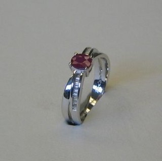 A lady's modern 18ct white gold dress ring set an oval cut ruby, supported by baguette cut diamonds