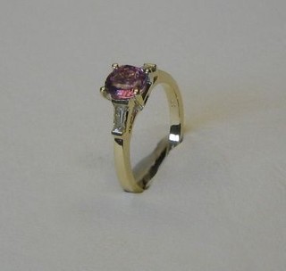 A lady's modern 18ct yellow gold dress ring set a circular pink sapphire, supported by 2 baguette cut diamonds