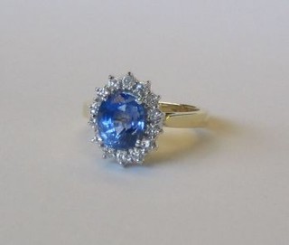 A lady's modern impressive 18ct gold dress ring set an oval Ceylonese sapphire (approx 3.50ct) supported by 14 diamonds