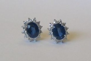 A pair of 18ct white gold ear studs set oval cut sapphires surrounded by diamonds