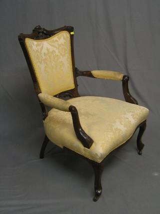 An Edwardian mahogany show frame open arm chair, upholstered yellow material with carved cresting rail, on cabriole supports