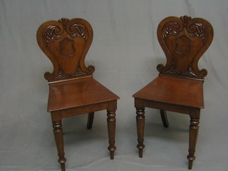 A pair of 19th Century mahogany hall chairs with solid seats, raised on turned supports