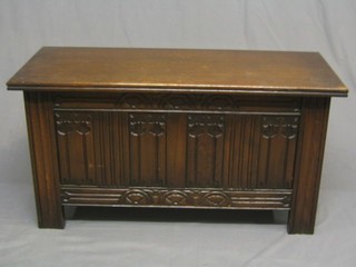 A 1930's oak coffer with hinged lid and linen fold decoration to the front 39"