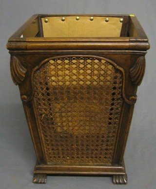 A carved walnutwood waste paper basket with cane panels raised on carved feet, 12"