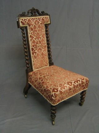 A Victorian carved rosewood nursing chair with spiral turned columns to the sides, upholstered seat and back and raised on spiral turned supports