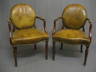 A pair of Georgian style mahogany open arm carver chairs the seats and backs upholstered green hide, raised on turned tapering supports