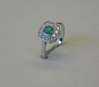 A lady's 18ct white gold dress ring  set a square cut emerald supported by numerous diamonds