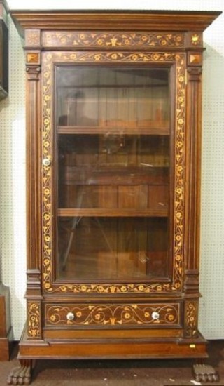 An Indian inlaid hardwood display cabinet with moulded cornice, the shelved interior enclosed by a bevelled plate panelled mirrored door, the base fitted a drawer, raised on hoof supports 41"