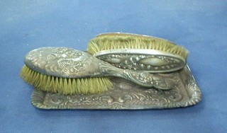 A rectangular embossed silver dressing table tray decorated angels, Chester 1918 10", 2 silver backed clothes brushes and a silver backed hand brush