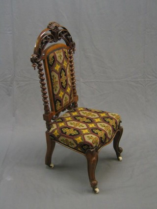 A Victorian walnutwood nursing chair with pierced arched cresting rail and spiral turned columns to the side, having a Berlin wool work seat and back, raised on French cabriole supports (some old worm)