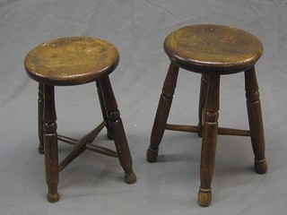 A pair of circular elm stools on turned supports with X framed stretchers