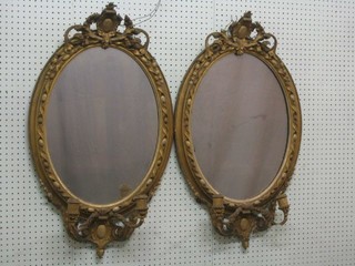 A pair of 19th Century oval plate wall mirrors contained in gilt plaster frames surmounted by a shield, the bases with 2 sconces 34"