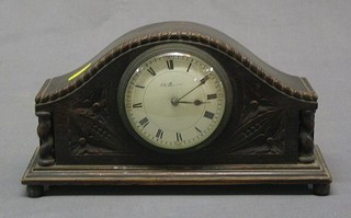 A 1930's 8 day bedroom timepiece with porcelain dial contained in a carved oak  arch shaped case by J W Benson