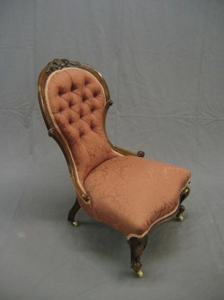 A Victorian carved walnut show frame nursing chair upholstered in pink buttoned material, on cabriole supports