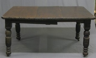 A Victorian heavily carved oak extending dining table, raised on turned supports with 2 extra leaves