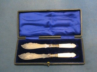 A pair of 19th Century silver plated butter knives with mother of pearl handles, cased