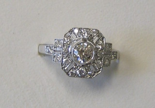 A lady's white gold dress ring set a large circular cut diamond surrounded by numerous diamonds and with 5 diamonds to the shoulders (approx 0.62ct)