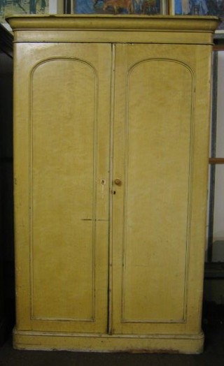 A Victorian white painted scumbled pine wardrobe with moulded cornice, fitted interior enclosed by panelled doors, raised on a platform base 52"