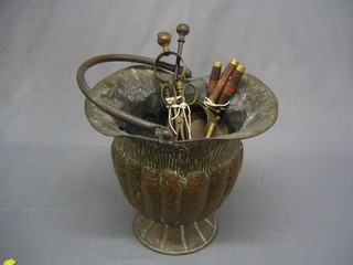 An Art Nouveau embossed copper coal bucket and a collection of fire side implements