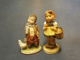 A Goebal figure of a standing girl with basket the base marked Goebel and impressed signature to base, together with an Italian biscuit porcelain of a standing boy (chip to base of jacket)