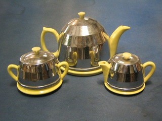 A 3 piece yellow glazed pottery tea service with chromium plated insulators with teapot, twin handled sugar bowl and cream jug