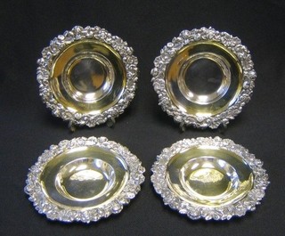 A set of 4 William IV circular silver saucers/dishes with silver gilt bowls, cast floral rims, 5" diameter, London 1822, makers mark REBE, 20 ozs