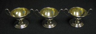 A set of 3 George III silver twin handled salts with parcel gilt interiors and armorial decoration, raised on circular spreading feet, London 1787, makers mark WS, 8 ozs
