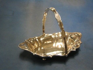 A shaped silver plated cake basket raised on 4 bun feet with swing handle