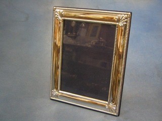 A modern plain silver easel photograph frame with bead work border 7" x 5"