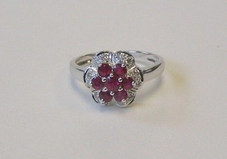 A lady's white gold cluster dress ring set 7 rubies supported by diamonds