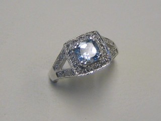 A lady's 18ct white gold dress ring set a square cut aquamarine supported by numerous diamonds