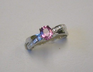 A lady's modern 18ct gold  dress ring set a pink sapphire supported by numerous baguette cut diamonds
