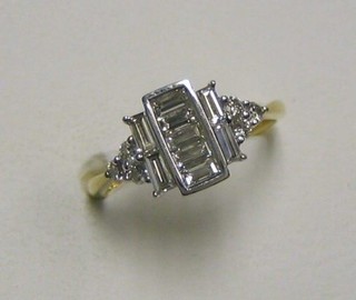 A lady's 18ct gold dress ring set 5 baguette cut diamonds, supported 4 baguette cut diamonds and having 3 diamonds to the shoulders