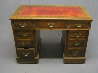 A honey oak kneehole pedestal desk with inset tooled leather writing surface above 9 drawers, 41"
