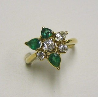 A lady's 18ct gold dress ring of floral design, set 3 diamonds and 3 tier cut emeralds