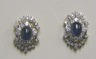 A handsome pair of lady's gold ear studs set cabouchon cut sapphires supported by numerous diamonds