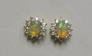 A pair of lady's gold ear studs set oval cut opals surrounded by 12 diamonds