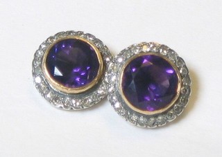 A pair of lady's circular amethyst ear studs supported by diamonds