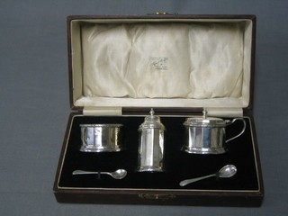 A silver 3 piece condiment set of cylindrical form with salt, pepper and mustard pot, Birmingham 1928, cased