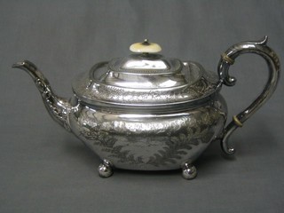 An engraved Britannia metal teapot raised on bun feet