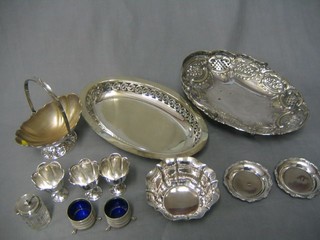 A pair of 19th Century circular silver plated salts, an oval embossed silver plated cake basket with swing handle, a boat shaped pierced basket and other silver plated items