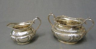 A Victorian embossed silver plated twin handled sugar bowl and matching cream jug