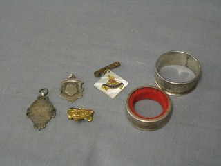 A silver wine bottle bib, a silver napkin ring, 2 silver sweetheart's brooches and 2 silver watch chain medallions