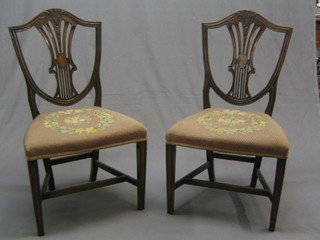 A pair of 19th Century Hepplewhite style camel back dining chairs, the seats upholstered in Berlin wool work, raised on square tapering supports