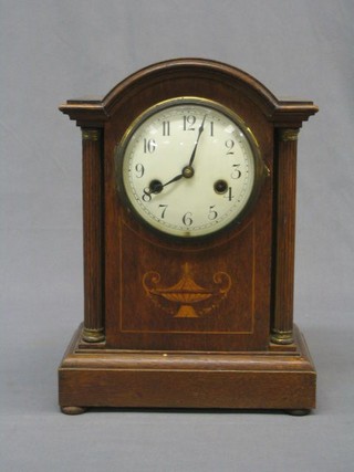 A  German Edwardian 8 day striking bracket clock with enamelled dial contained in an arched inlaid mahogany case flanked by a pair of pillars, on bun feet