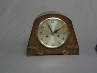 A 1930's striking mantel clock with silvered dial and Arabic numerals contained in an oak arched case