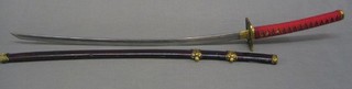 A reproduction Katana contained in a lacquered scabbard with red decoration to the grip 44"