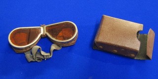 A pair of orange tinted goggles with fibre case