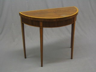 A Georgian mahogany demi-lune card table with crossbanded top, raised on square tapering supports 35"